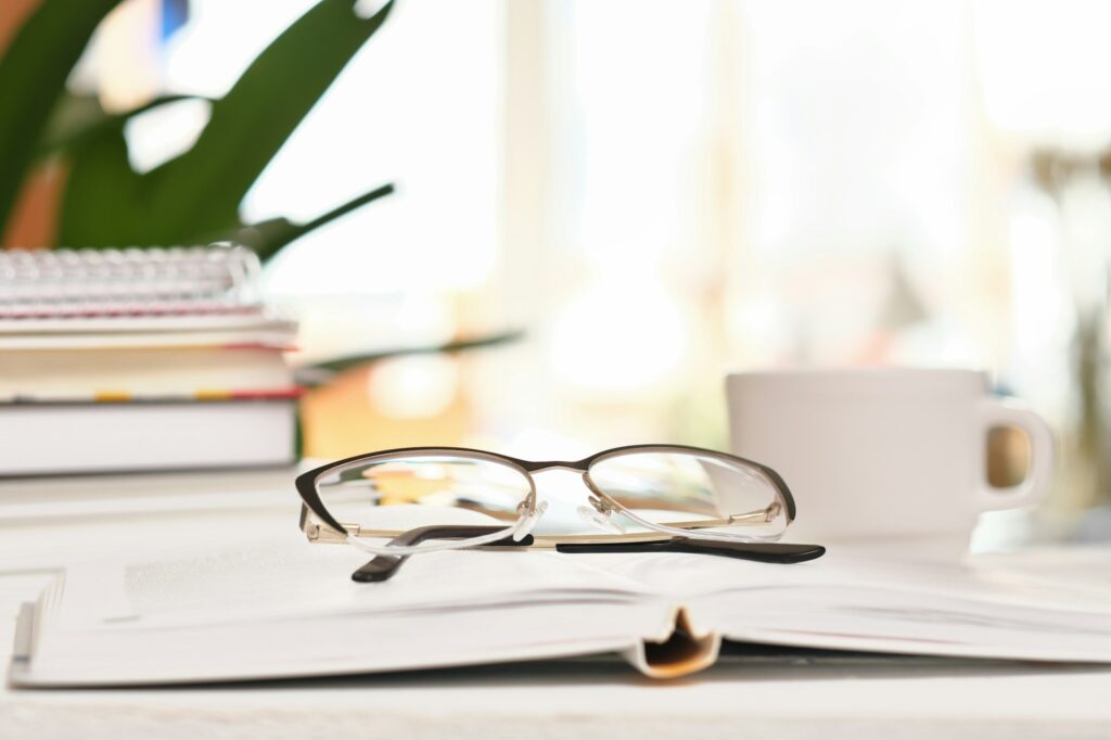 eyeglasses and books on a table and cup of coffee. cognition and research concept.