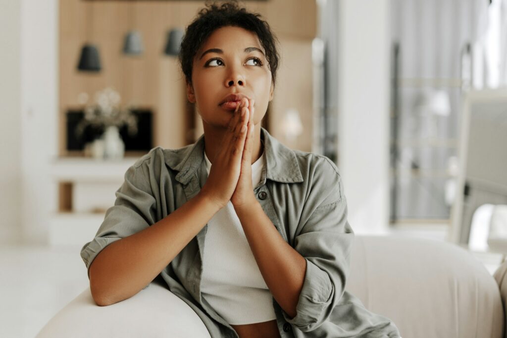 Young woman holding hands in prayer asking for help